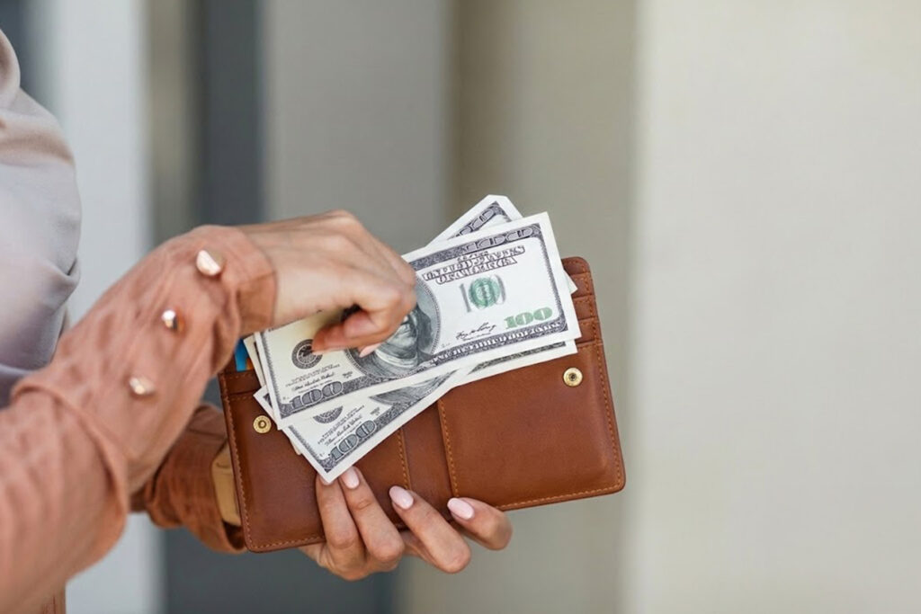 Lady pulling hundred dollar bills out of her wallet